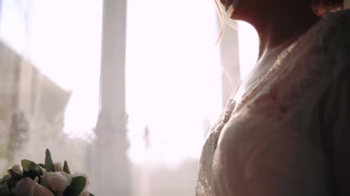 The Morning of the Bride in a White Peignoir Holds in Her Hands a Wedding Bouquet of Roses. . Close