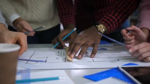 Business People Drawing on Blueprint at Table