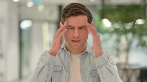 Young Adult Man Rubbing Temples Experiencing Headache