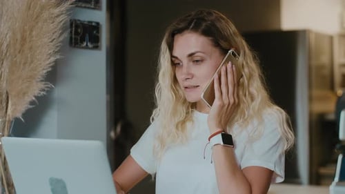 Close up pretty caucasian woman talking by phone during working with laptop