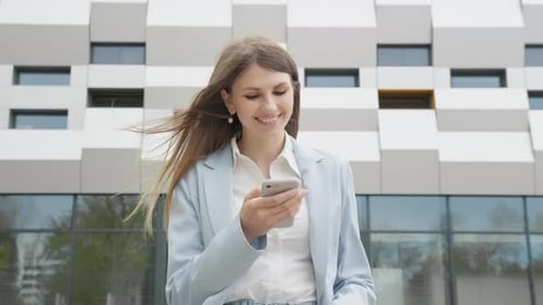Smiling Woman Using Phone Near Modern Building