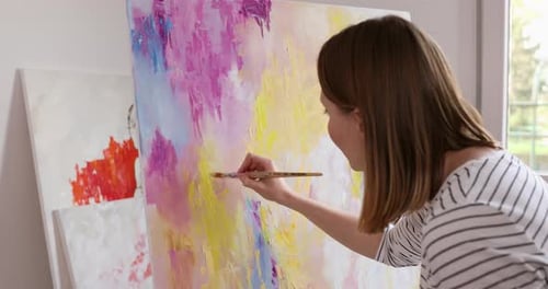 Young artist working on colorful painting in studio