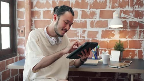Young Adult Using Tablet at Desk Indoors
