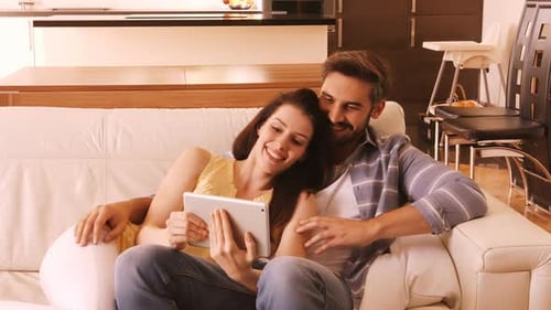 Couple Relaxing on Sofa With Tablet at Home