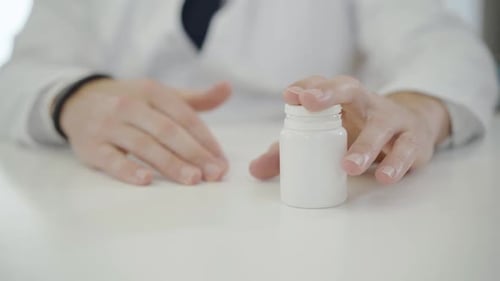 Close-up of Male Hands Passing Jar with Pills To Unrecognizable Patient. Doctor Giving Remedy To