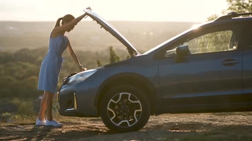 Woman Opens Car Hood on Hilltop During Sunset