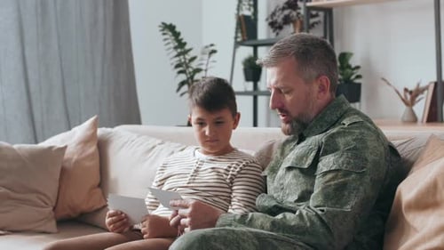 Soldier and Son Looking at Photographs Together