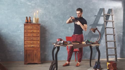 Stylish Artisan Inspecting Fine Leather Shoes in Workshop