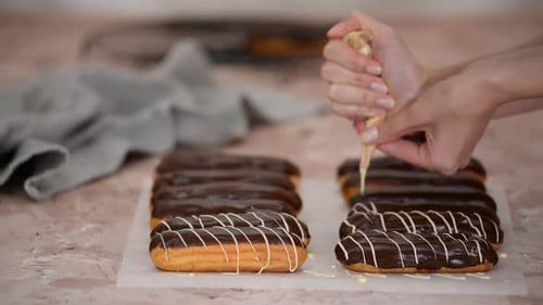 Piping Cream Filling onto Chocolate Eclairs