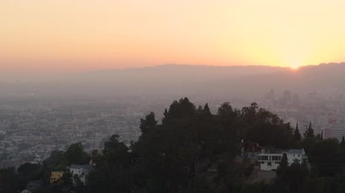 Aerial of houses on mountain top overlooking cityscape at sunset
