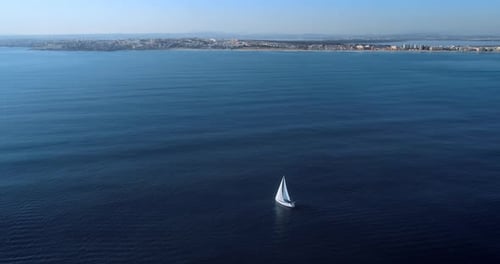 Aerial View of Yacht Sailing Slow Close to the City Coastline and Beach Calm Day