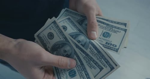 Hands Counting Stack of United States Hundred Dollar Bills