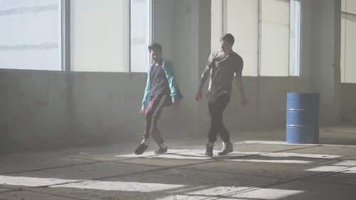 Zwei Freunde erfolgreicher Tänzer tanzen Breakdance in einem verlassenen, staubigen Gebäude