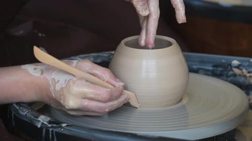 Gros plan d'un céramiste méconnaissable formant un vase en argile fabriqué à la main avec un outil spécial et un potier