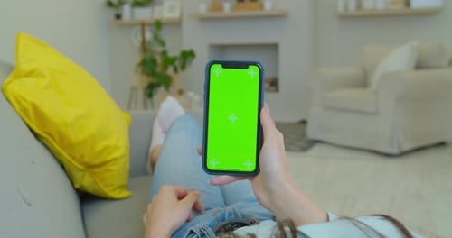 Woman at Home Lying on a Couch Using Smartphone with Green Screen. Girl Using Mobile Phone, Internet