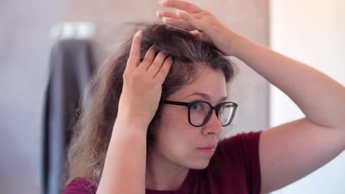 Woman Examines Gray Roots in Mirror Close Up