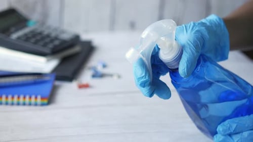 Gloved Person Holding Spray Bottle with Blue Liquid