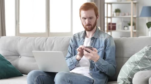Creative Beard Man Working on Laptop and Smartphone in Office