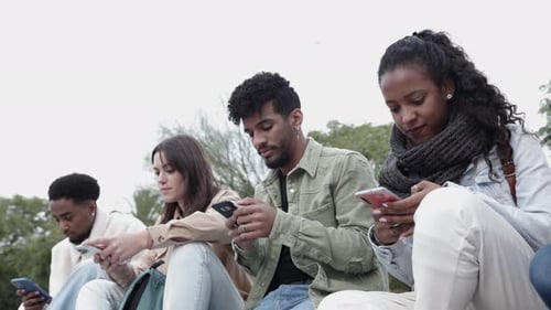 Young Adults Using Smartphones Together Outdoors