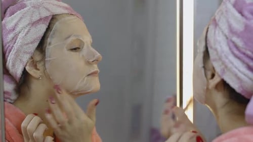 Woman Applying Cosmetic Face Mask in Bathroom. Skincare Spa. Facial Mask