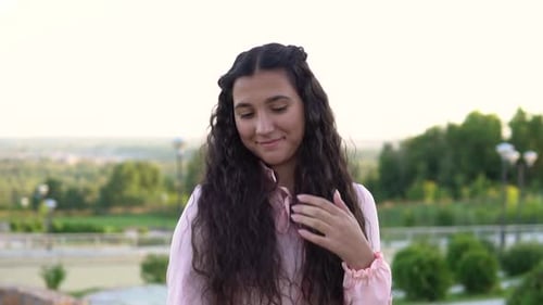 A Young Girl Poses Standing in a Park on a City Background