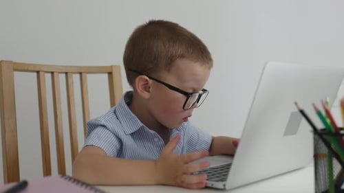 Intelligentes Baby Boy Kind mit Brille arbeitet am Laptop Computer Sitztisch Zimmer