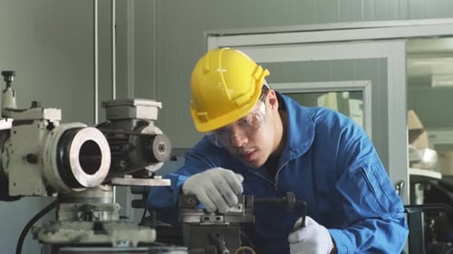 Asian mechanical technicians workers working on milling machine and operating in industrial factory.
