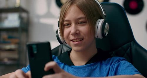 Un adolescente habla por auriculares inalámbricos mientras hace los deberes por teléfono