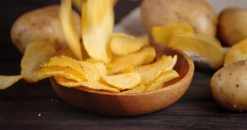 Golden Potato Chips Poured into Wooden Bowl