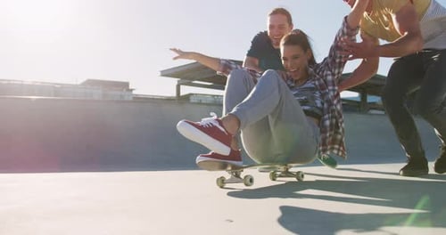 Smiling Woman Rides Skateboard Pushed by Two Friends