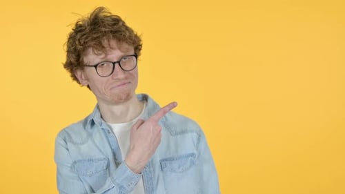 Man Points to the Side on Yellow Background