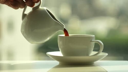 Pouring Hot Tea into Cup at Breakfast Time