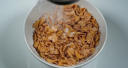Sugar Being Poured Over Cornflakes in a Bowl
