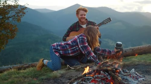 Couple Camping Playing Guitar by Mountain Campfire