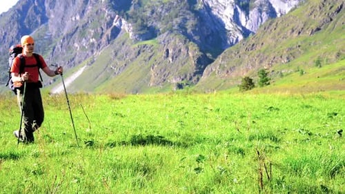 Hiking Man Walking on Green Mountain Meadow with Backpack