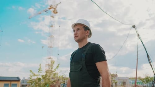 A Builder in a Helmet Is Walking and Inspecting the Construction Site.