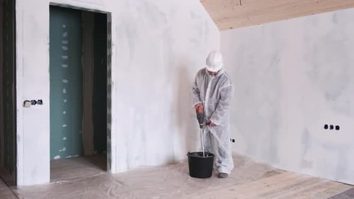 Man Mixes Plaster with Drill in Room