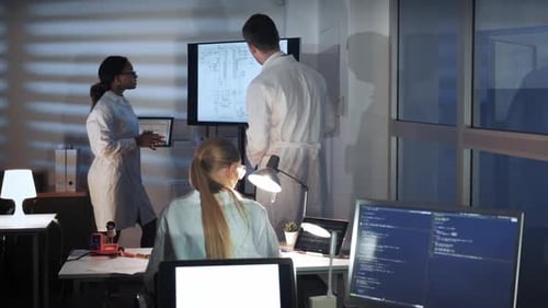 Engineers Discussing Circuit Diagram in Office at Night