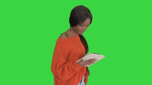 Smiling African American Woman Using Tablet Pc While Walking on a Green Screen, Chroma Key