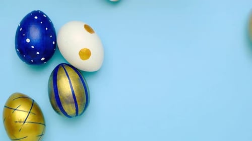 Easter Eggs are Rolling Knocking Each Other on Blue Table