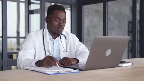 Young Doctor Works at Laptop in Office