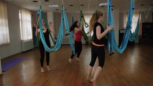A Group of Young People Do Relaxing Exercises on a Hammock in the Gym