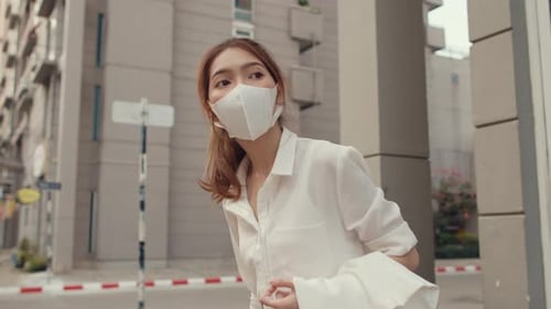 Businesswoman in fashion office clothes wear medical face mask walking alone outdoor in city