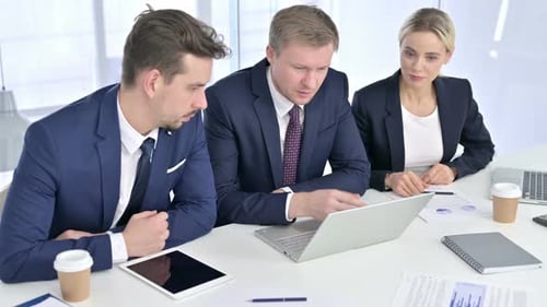 Serious Professional Team Discussing and Working on Laptop