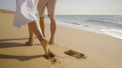 Couple Walking Barefoot Together Along Sandy Beach Coastline
