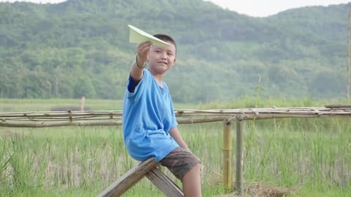 Boy with Paper Airplane in Serene Rural Setting