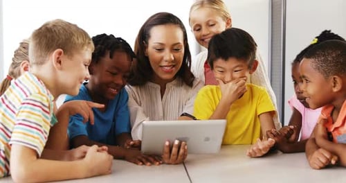 Teacher teaching school kids on digital tablet in classroom