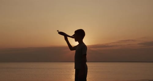 Boy with Toy Airplane at Sunset Near Ocean