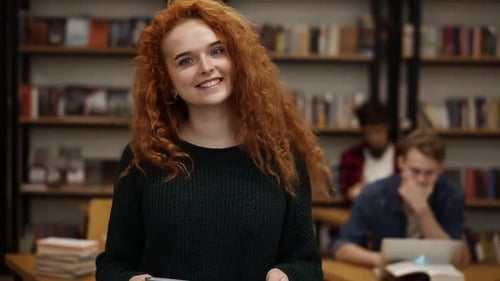 Portrait of an Attractive Long Red Haired European Girl Student Standing in High School Library