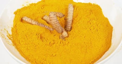 Turmeric, curcuma longa, Root falling on curcuma Powder, Indian Spice, Slow Motion 4K